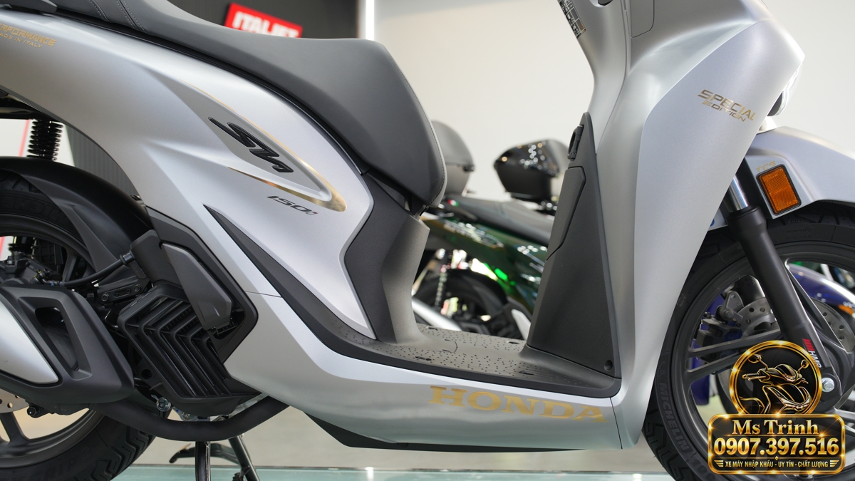 Sàn để chân Honda SH150i Ý xám bạc và logo vàng Sàn để chân phẳng của Honda SH150i Ý xám bạc 2027 với ốp thân và chữ Honda màu vàng